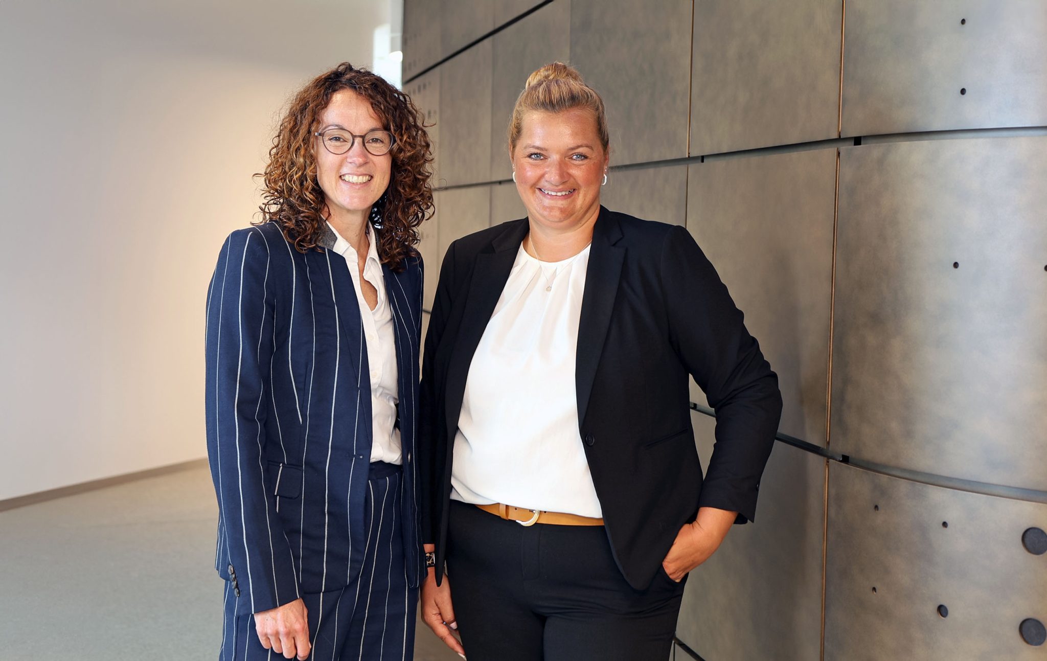 Zwei Generalbevollmächtigte der Volksbank Mittelhessen in Business-Kleidung in einem modernen, minimalistischen Interior.