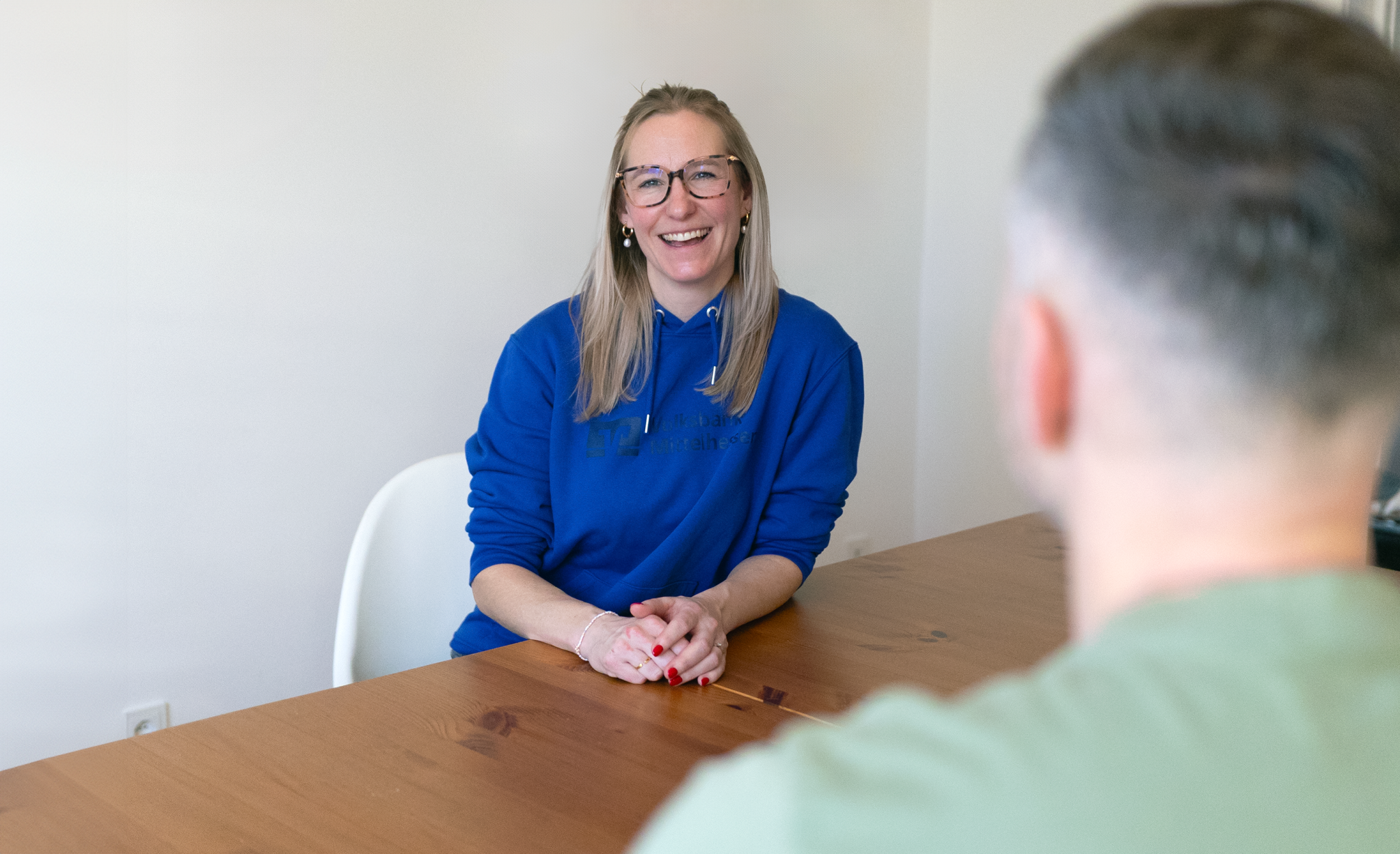 Die FamilyBuddy‑Beraterin der Volksbank Mittelhessen führt in entspannter Atmosphäre ein Beratungsgespräch mit einem Kunden an einem Tisch.