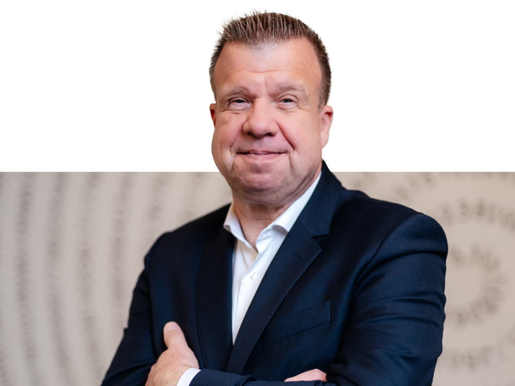 Ein Vorstandssprecher der Volksbank Mittelhessen steht im Business‑Anzug vor einem modernen Hintergrund.