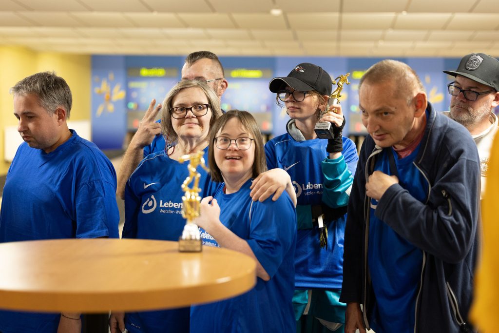 Teilnehmende der hessischen Lebenshilfewerkstätten zeigen stolz ihre Pokale beim inklusiven Kegel‑Turnier.