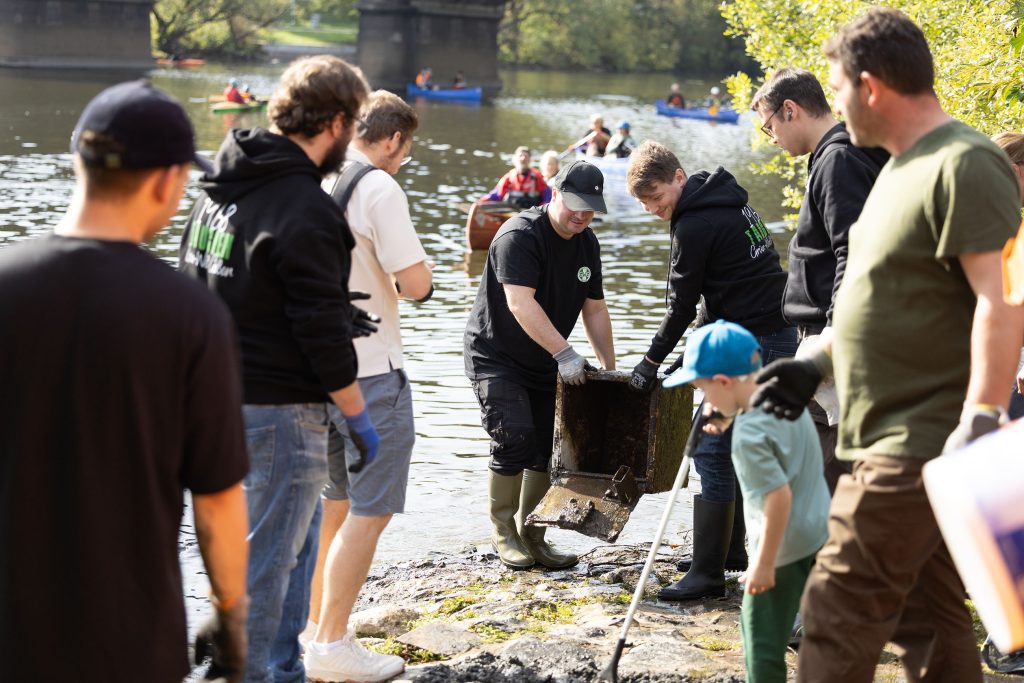 Mitglieder der Tauchsportabteilung von Grün‑Weiß Gießen und weitere Helfer bergen Müll aus der Lahn und bringen Fundstücke ans Ufer.