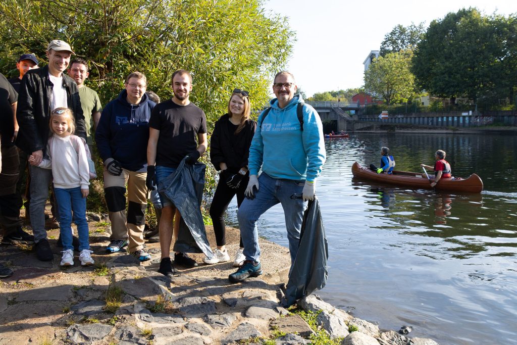 Ein Team der Volksbank Mittelhessen sammelt Müll am Lahnufer im Rahmen der gemeinsamen Lahnreinigung mehrerer Wassersportvereine.