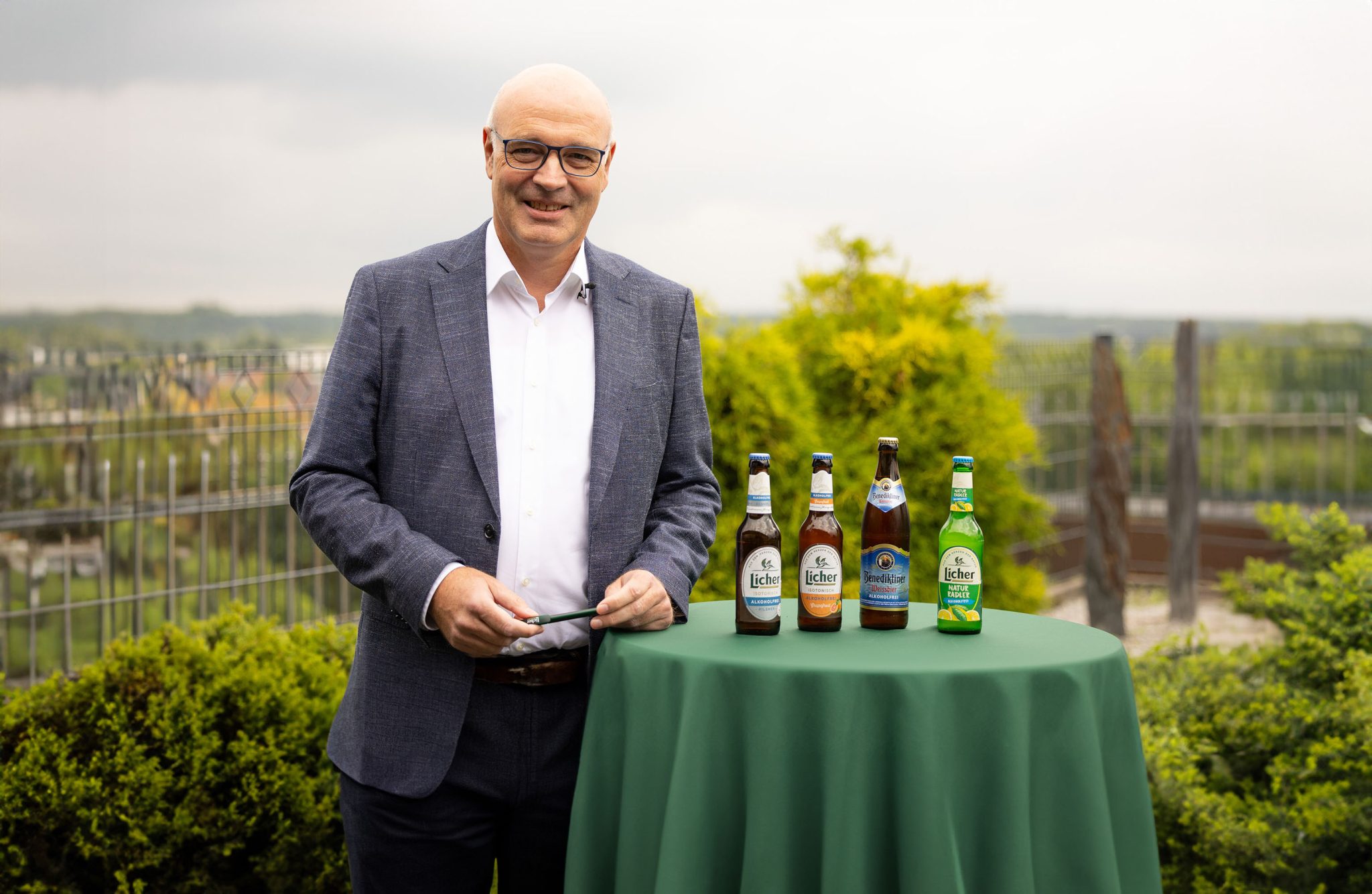Der Geschäftsführer präsentiert verschiedene Licher-Biersorten auf einem runden Stehtisch im Außenbereich.