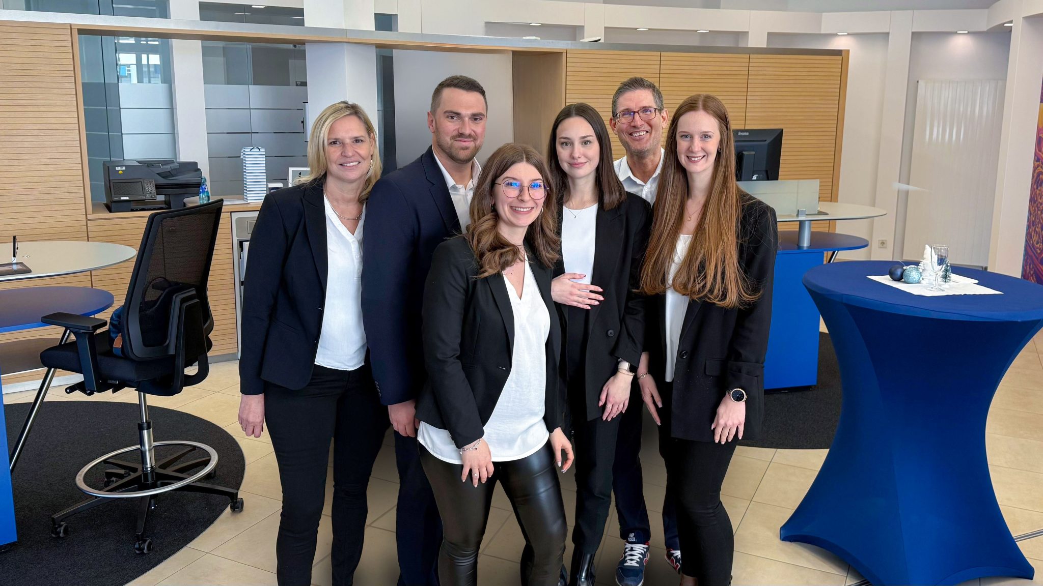 Das Team der neuen Volksbank Mittelhessen Filiale in Wehrheim steht gemeinsam im modern gestalteten Beratungsbereich der Bank.