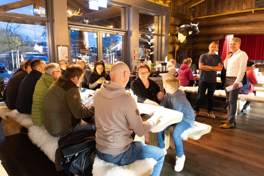 Gemütliches Interior im Timberjacks Restaurant Bad Hersfeld mit großen Holzelementen, warmem Licht und langen Tischen, an denen Gäste in rustikaler Western‑Atmosphäre gemeinsam speisen.